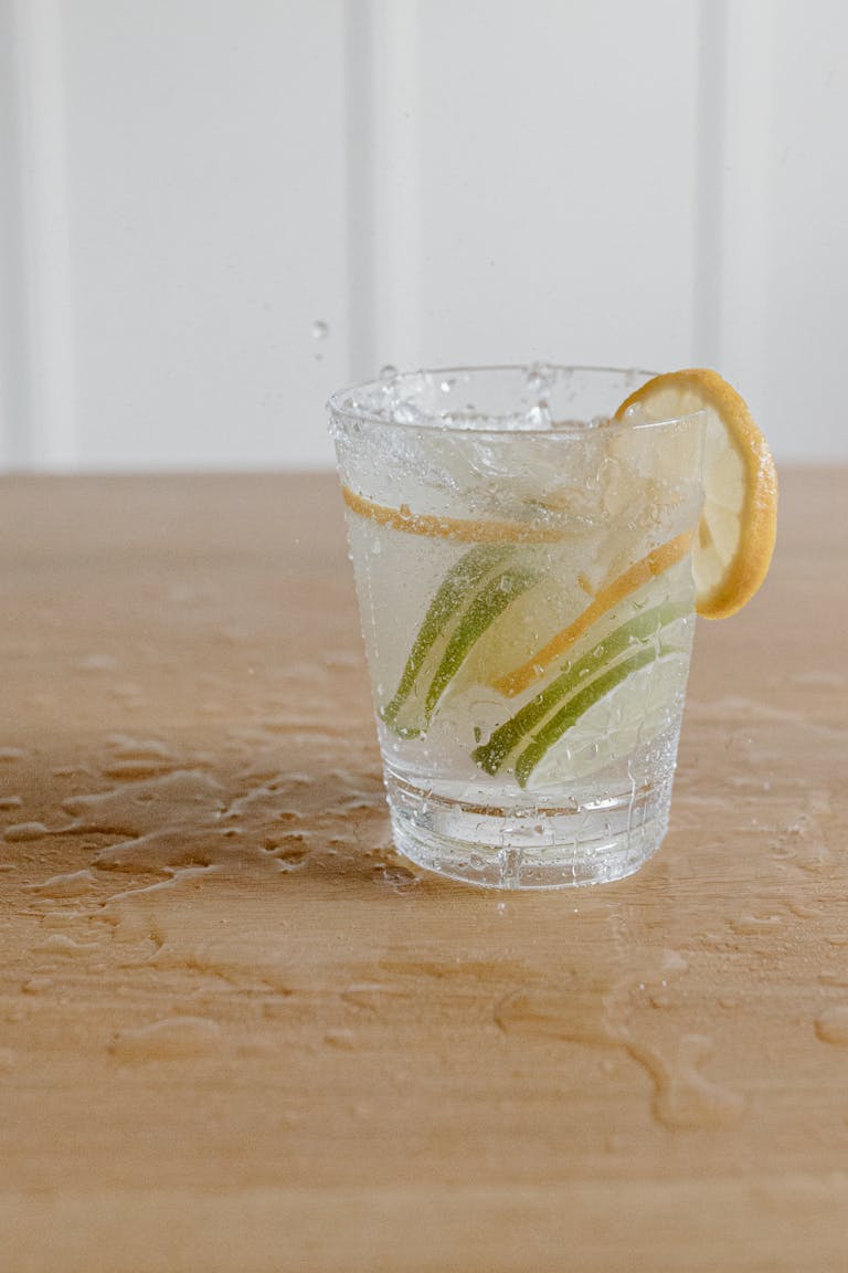 A refreshing drink with lemon and lime slices in a glass on a wooden table.