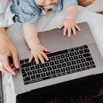 Top view of a parent and a child's hands on a laptop keyboard, symbolizing digital learning.