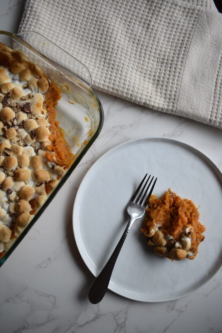 Whole roasted sweet potato topped with toasted marshmallows and chopped pecans