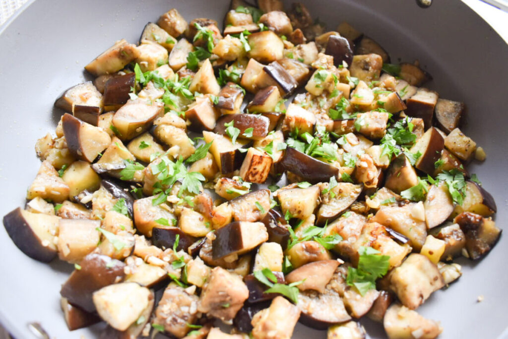 Garlic sautéed eggplant cooking in a skillet
