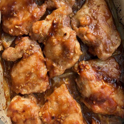 Sticky honey garlic soy baked chicken thighs in white baking dish