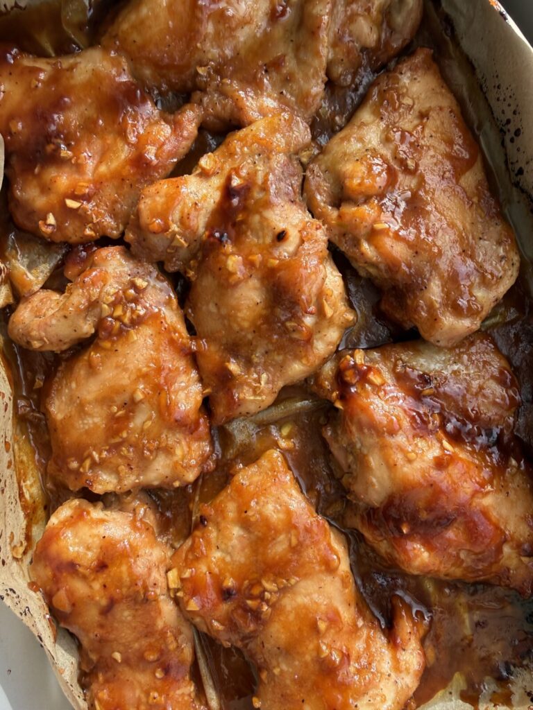Sticky honey garlic soy baked chicken thighs in white baking dish