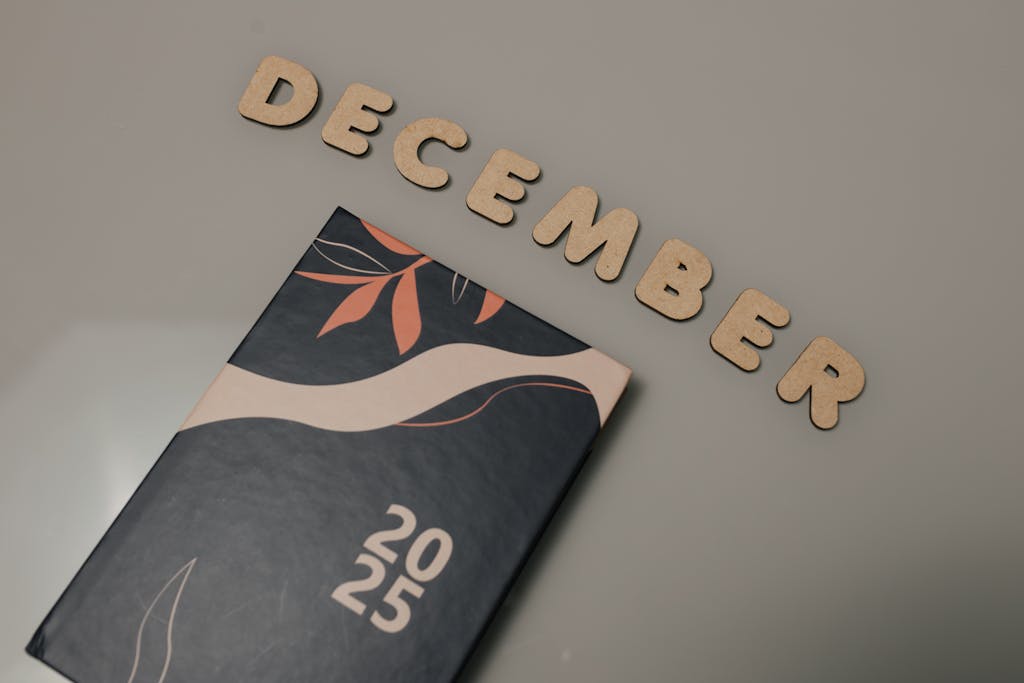 A 2025 planner displayed with wooden letters spelling 'December' on a neutral background.