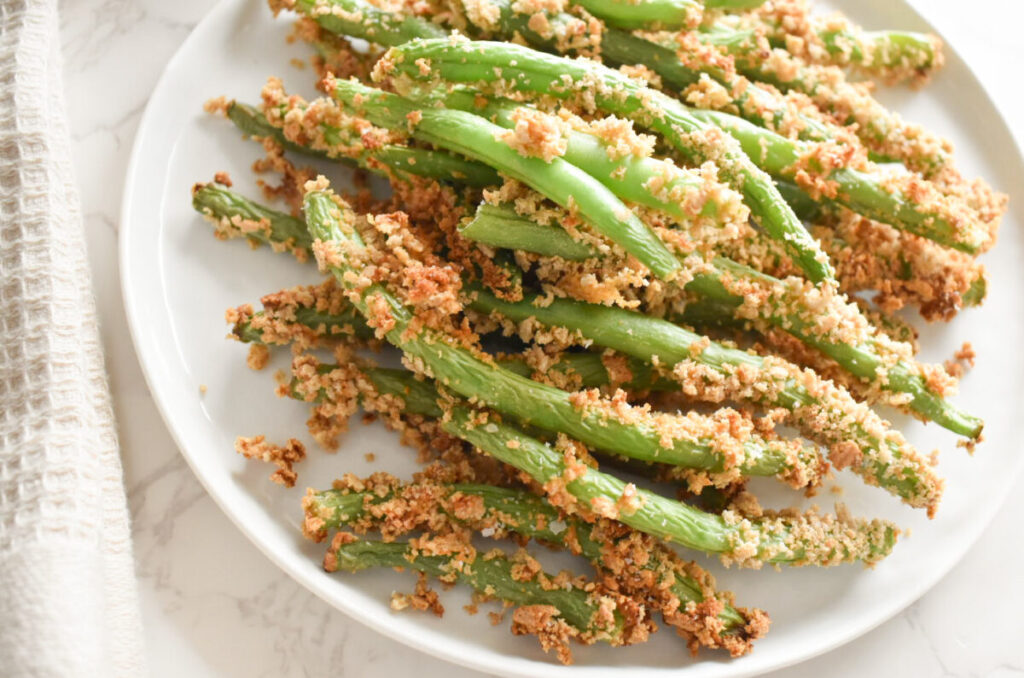 Close-up of crispy coated green beans with flaky salt.