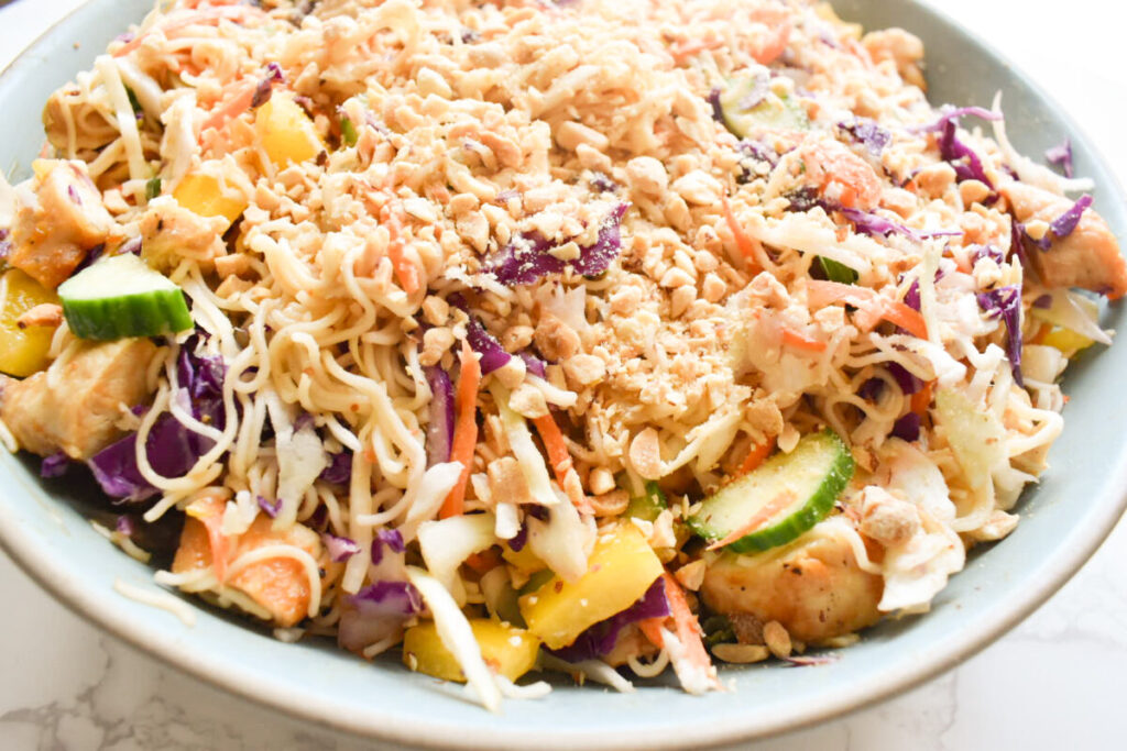 Close-up of peanut dressing being poured over ramen salad