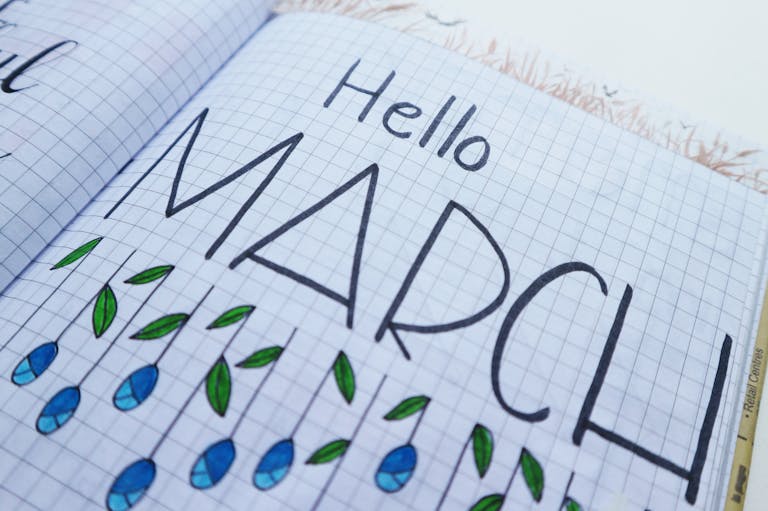 Open notebook with "Hello March" illustration featuring colorful raindrops and leaves.
