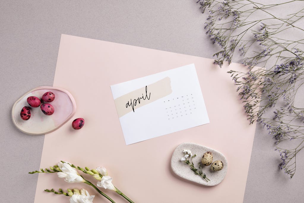 Flat lay of April calendar with florals, painted eggs, and pastel colors for Easter decoration.