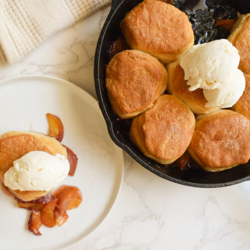 Cast iron peach cobbler with golden biscuit topping