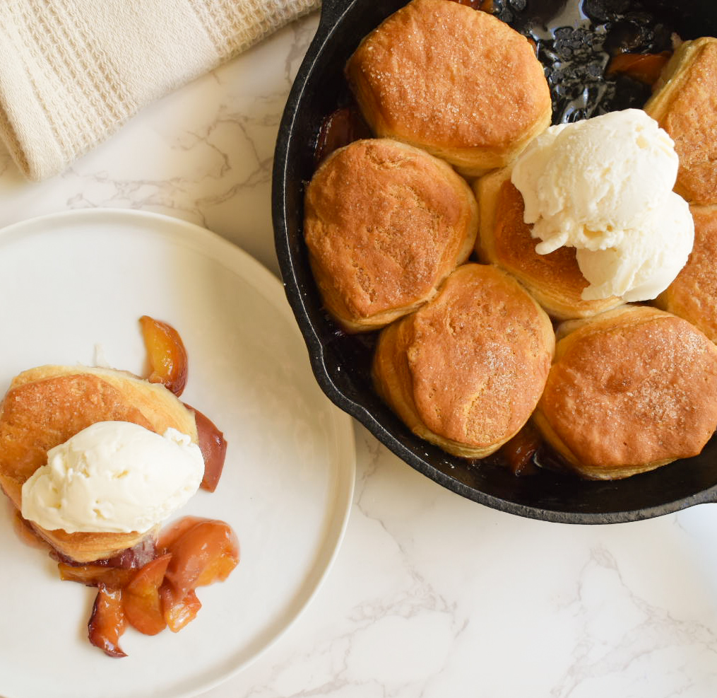 Cast iron peach cobbler with golden biscuit topping
