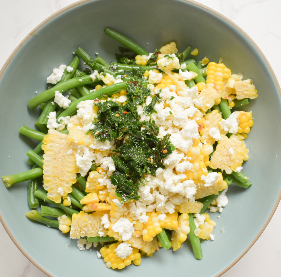Healthy summer vegetable salad made with green beans, corn, feta, and herbs