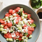 Watermelon Ball Salad with cucumber, feta, mint and balsamic glaze in a white serving bowl