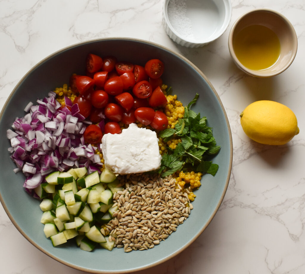 Close-up of pearl couscous salad with feta cheese and fresh vegetables