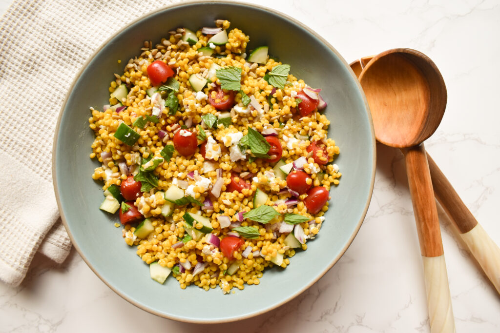 Mediterranean Israeli couscous salad with cucumber, tomatoes, feta, mint, and sunflower seeds