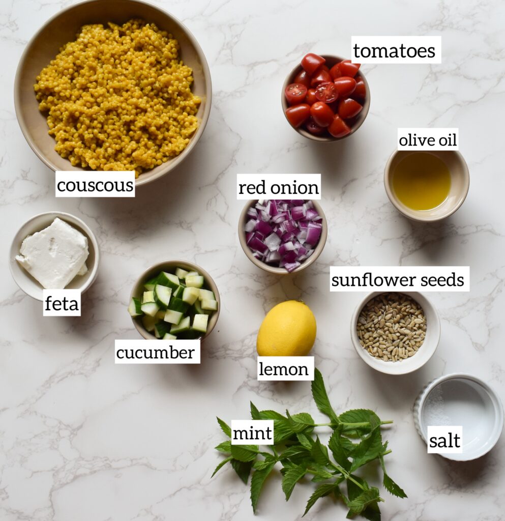 Ingredients in Israeli couscous salad with cucumber, tomato, red onion, feta, and mint