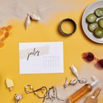 Summer-themed flat lay with vacation essentials like sunglasses, fruits, and calendar on sand.