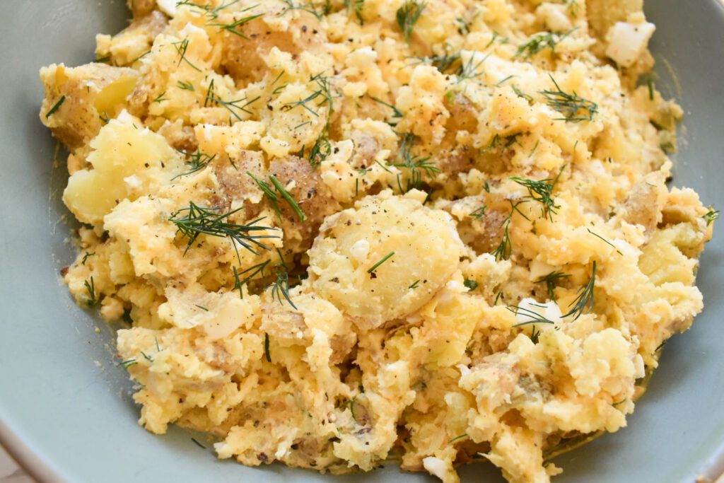 Creamy baby Yukon potato salad with eggs and fresh herbs in a serving bowl