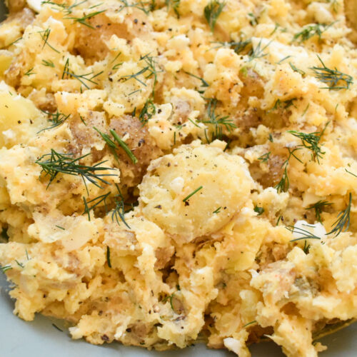 Creamy baby Yukon potato salad with eggs and fresh herbs in a serving bowl