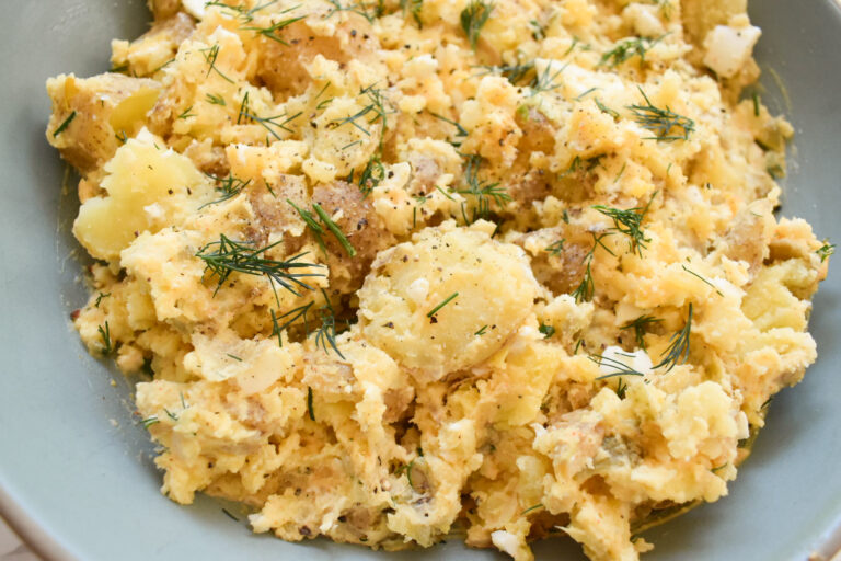 Creamy baby Yukon potato salad with eggs and fresh herbs in a serving bowl