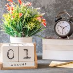 Elegant desktop setup with a calendar, clock, books, and a floral arrangement.