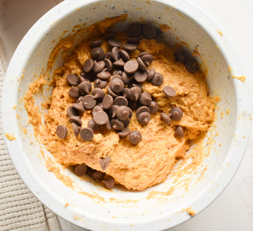 Pumpkin bread batter folding in chocolate chips in a large bowl.