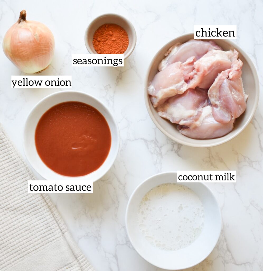 Ingredients for coconut chicken tikka masala, including chicken thighs, coconut milk, tomato sauce, onion, and spices.